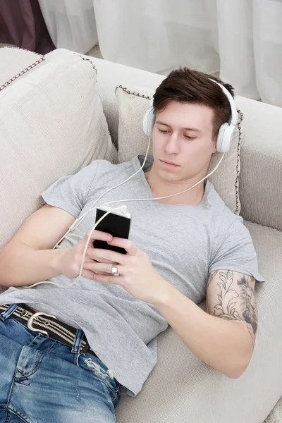 Man on couch watches a movie on mobile phone — Stock Photo, Image