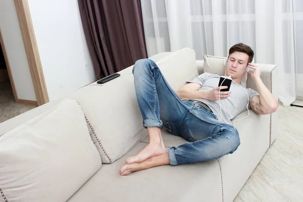 Glücklicher junger Mann mit Smartphone beim Musikhören — Stockfoto