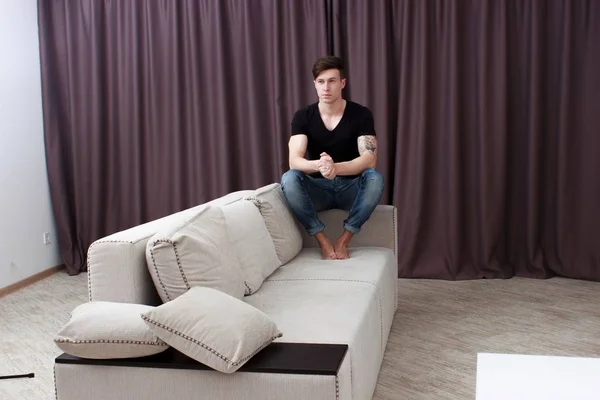 Porträt eines lässig müden Mannes, der zu Hause auf einer Couch sitzt — Stockfoto