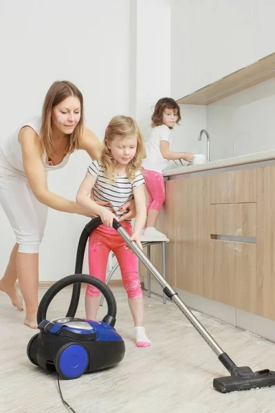 Trochę piękna dziewczyna uśmiechający się kolejny z odkurzacza w domu. — Zdjęcie stockowe