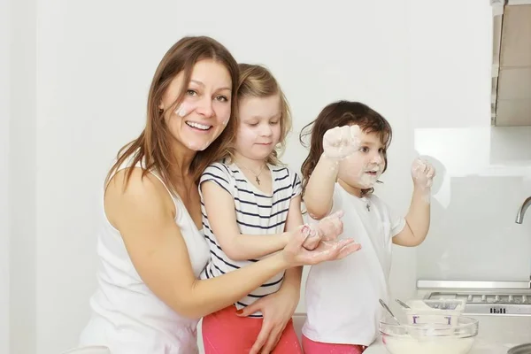 Madre con sus hijos de 5 años cocinando pastel de vacaciones en la cocina — Foto de Stock