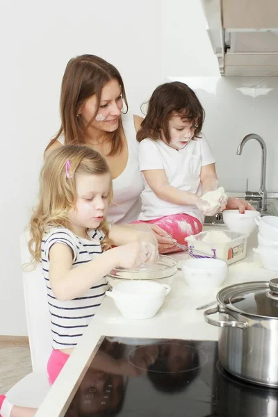 Mother with her 5 years old kids cooking holiday pie in the kitchen — Stock Photo, Image