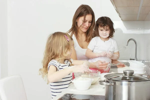 Madre con i suoi bambini di 5 anni che cucinano torta di vacanza in cucina — Foto Stock