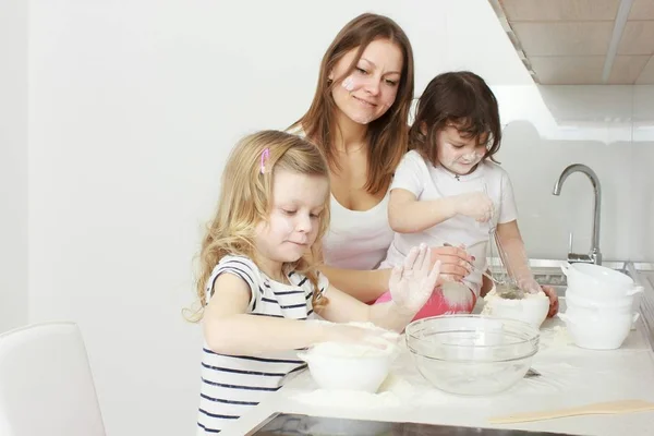 Мама со своими 5-летними детьми готовит праздничный пирог на кухне — стоковое фото