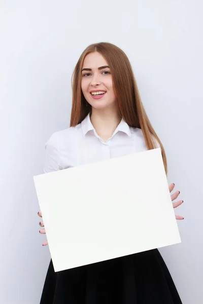 Publicidade. Jovem mulher sorridente mostrar placa em branco no fundo branco . — Fotografia de Stock