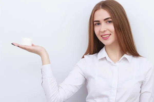 Jonge mooie lachende vrouw met cosmetica fles geïsoleerd op witte achtergrond — Stockfoto