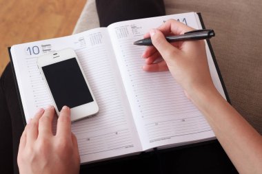 Kadın iş gündem defterini içine cep telefonundan kişi listesi yazma