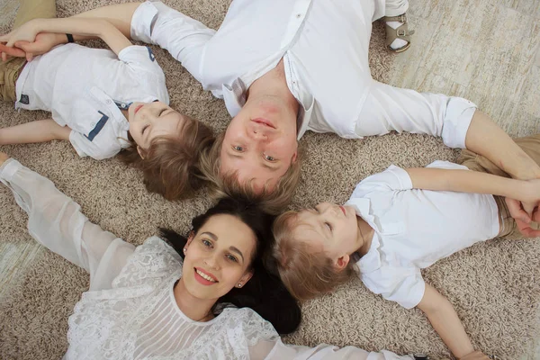 Blick von oben auf schöne junge Eltern, deren süße kleine Söhne auf dem Boden liegen — Stockfoto