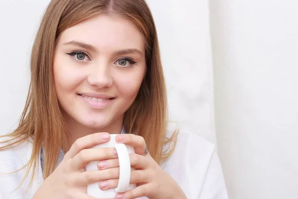 Woman sitting on couch in her living room and drinking coffee — Stock Photo, Image