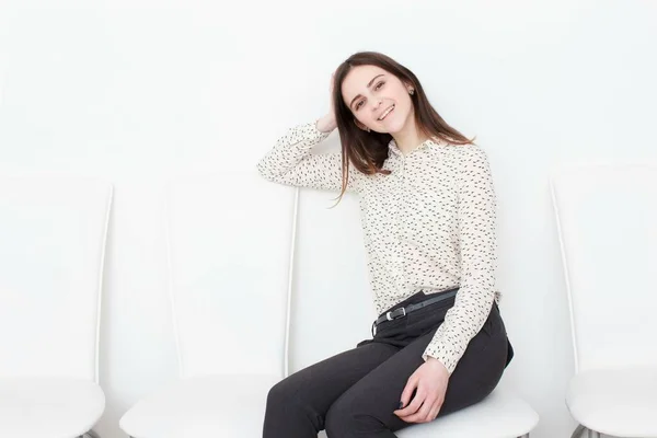 Attraente ragazza seduta sulla sedia bianca moderna e rilassarsi a casa — Foto Stock