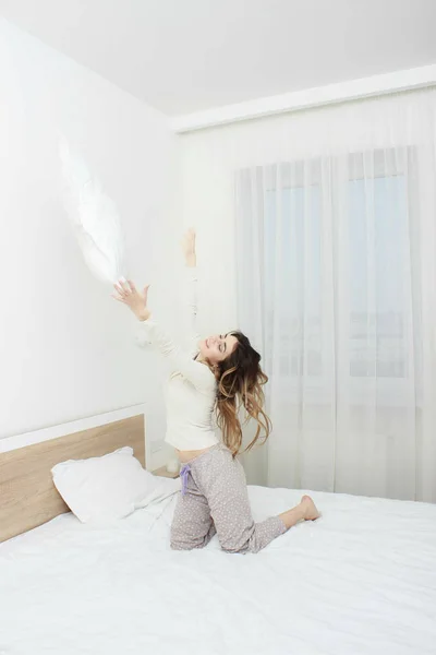 Kadın gülümsüyor ve yastık atma pijama — Stok fotoğraf