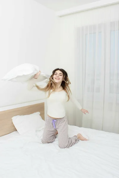 Mujer en pijama sonriendo y tirando una almohada —  Fotos de Stock