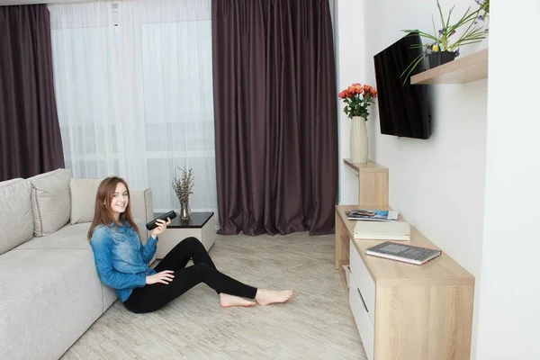 Young Woman Sitting Sits on the floor Watching Television. — Stock Photo, Image