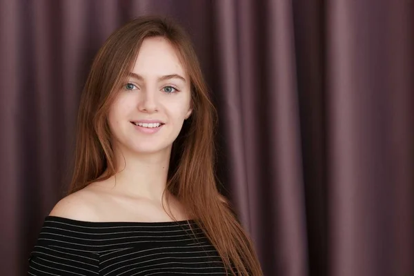 Chica joven con vestido negro contra cortinas. Mirando a la cámara — Foto de Stock