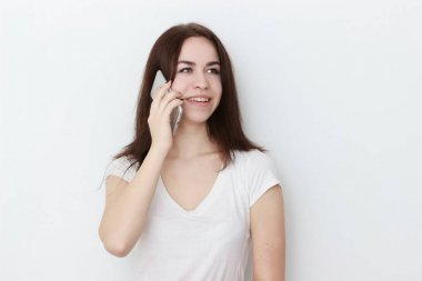 Telefonla konuşan gülümseyen kız öğrenci beyaz bir arka planda izole edilmiş.