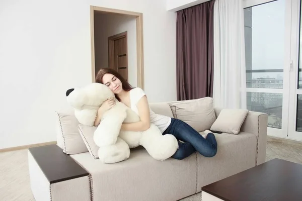 Joven mujer en el sofá en las manos blanco osos de peluche —  Fotos de Stock