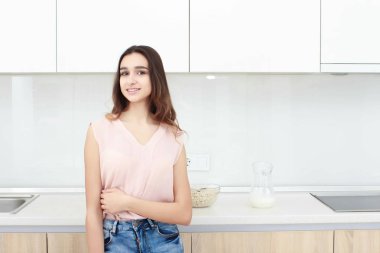 Ciddi tutum. Genç gülümseyen Bayan bir mutfakta ayakta.