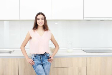 Ciddi tutum. Genç gülümseyen Bayan bir mutfakta ayakta.