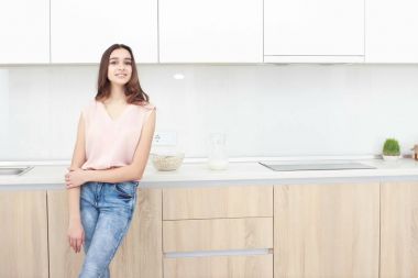 Ciddi tutum. Genç gülümseyen Bayan bir mutfakta ayakta.