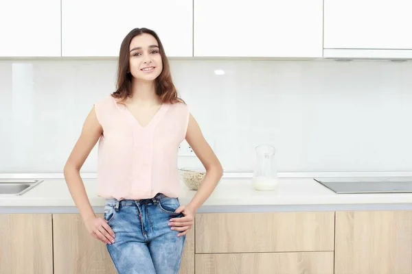 Серьезное отношение. Молодая улыбающаяся леди, стоящая на кухне . — стоковое фото