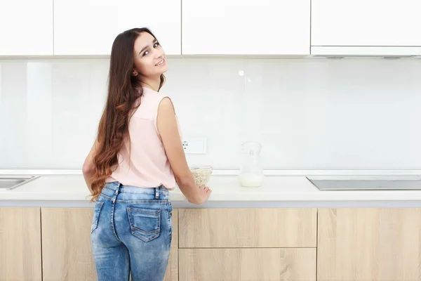 Серьезное отношение. Молодая улыбающаяся леди, стоящая на кухне . — стоковое фото