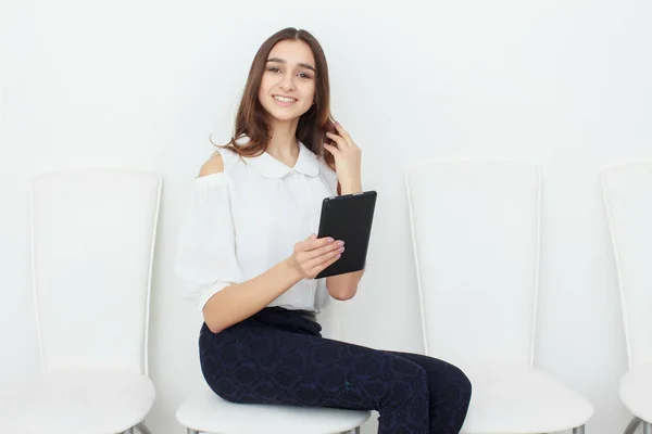 Jovem sentada em uma cadeira e usando um tablet — Fotografia de Stock