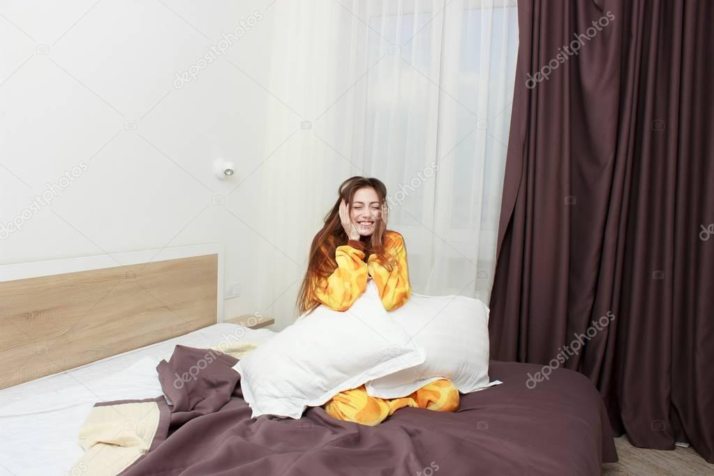 Lustige Mädchen in kigurumi Pyjamas springen auf dem Bett — Stockfoto