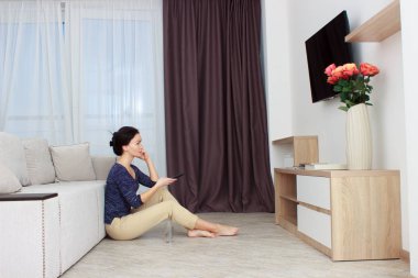 evde TV izlerken, bir uzaktan kumanda tutan kadın.