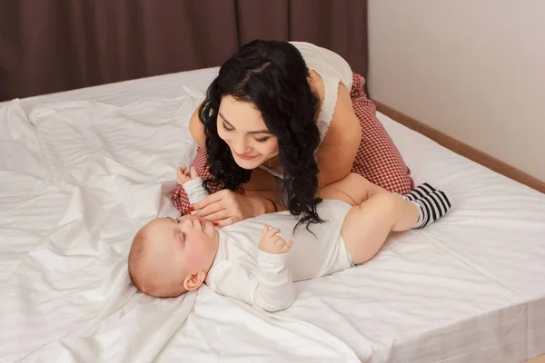 Felice madre sorridente e bambino sdraiato sul letto — Foto Stock