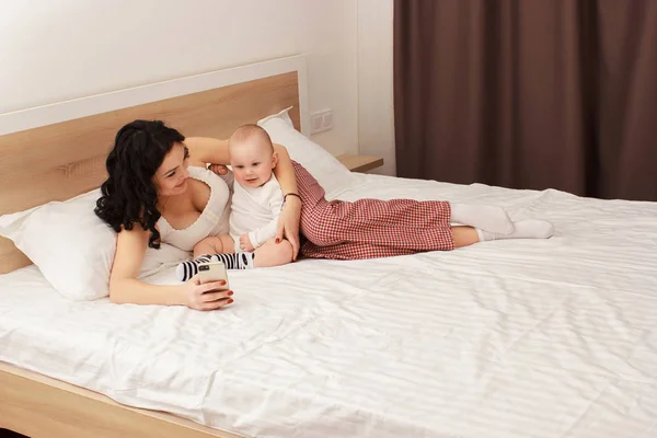 Счастливая улыбающаяся мать и ребенок лежат на кровати — стоковое фото