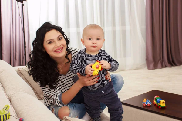 Junge Mutter und ihr Sohn spielen und lesen ein Buch auf dem Sofa, Lebensstil — Stockfoto