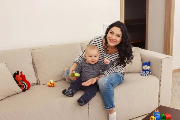 Joven madre y su hijo jugar y leer un libro sobre sofá, estilo de vida —  Fotos de Stock