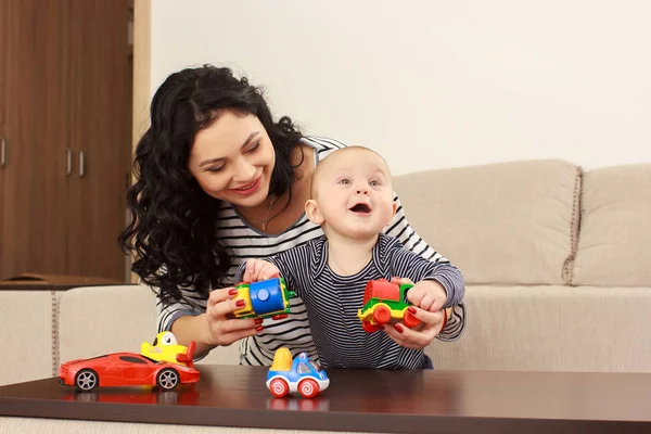 Młoda matka i jej syn grać i czytając książkę na kanapie, styl życia — Zdjęcie stockowe