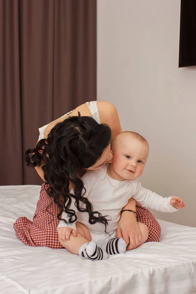 Happy smiling mother and baby lying on bed — Stock Photo, Image