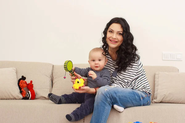 Mladá matka a její syn hrát a číst knihu na pohovce, životní styl — Stock fotografie