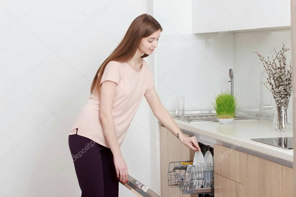 Kitchen Woman. Girl in the kitchen using dishwasher