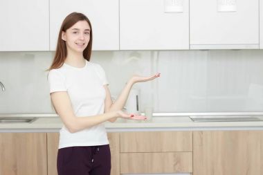 Ürün mesajınız için kadın gösteren görüntülenirken kopya alanı. Mutfakta ayakta ve gülümseyen siyah saçlı genç ve güzel kadın.