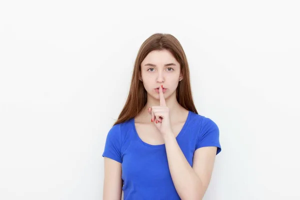 Porträtt av ung kvinna att hålla fingret på hennes läppar och ber att hålla tyst, isolerade över vit bakgrund — Stockfoto