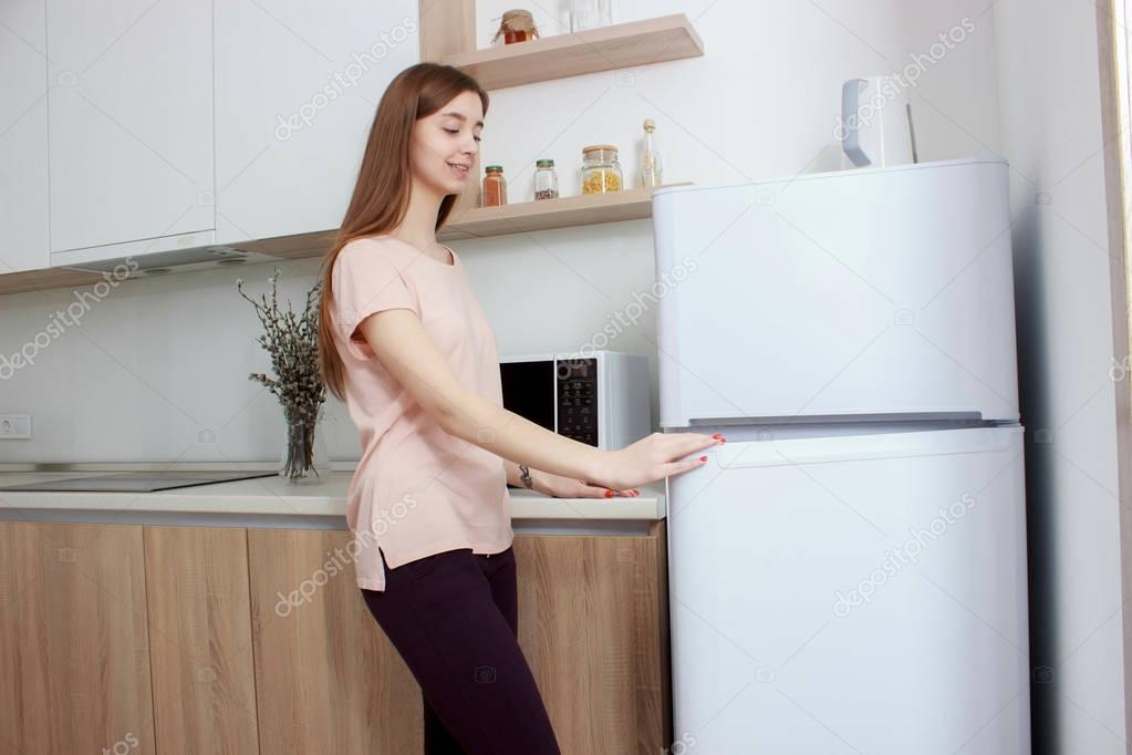 Happy woman looking for something in the fridge at home