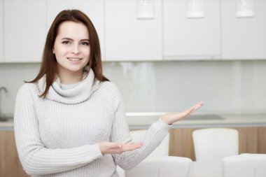 Ciddi tutum. Genç gülümseyen Bayan bir mutfakta ayakta.