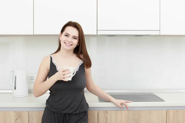 Junge Frau mit schwarzem Haar trinkt Kaffee in der Küche — Stockfoto