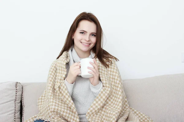 Ragazza seduta sul divano in soggiorno con tazza di tè — Foto Stock