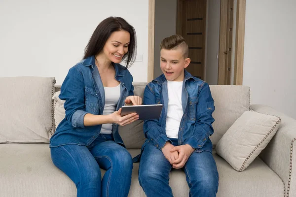 Счастливая семья, сидящая на диване и пользующаяся цифровым планшетом дома — стоковое фото