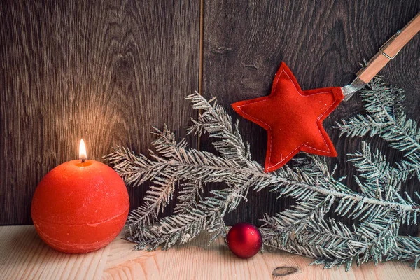 Duas velas vermelhas com decoração de Natal no fundo de madeira — Fotografia de Stock