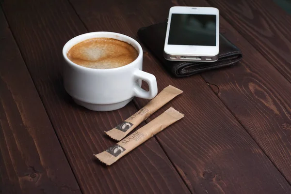 Smartphone with notebook and cup of strong coffee on wooden background — Stock Photo, Image
