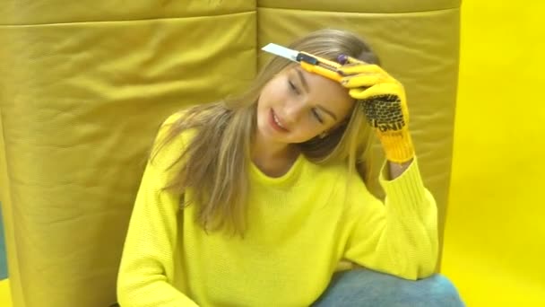Hermosa chica constructora sosteniendo un pincel y posando en la cámara. sobre fondo amarillo — Vídeo de stock