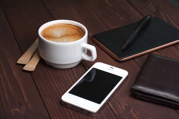 Смартфон с ноутбуком и чашкой крепкого кофе на деревянном фоне
