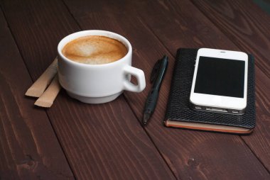 Defter ve ahşap arka plan üzerinde güçlü kahve ile Smartphone
