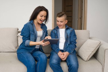 Mutlu aile kanepede oturan ve evde dijital tablet kullanma