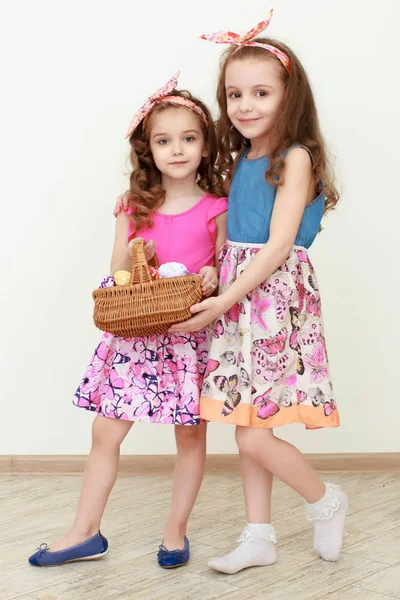 Hermanas niñas están sosteniendo cesta con huevos pintados . —  Fotos de Stock
